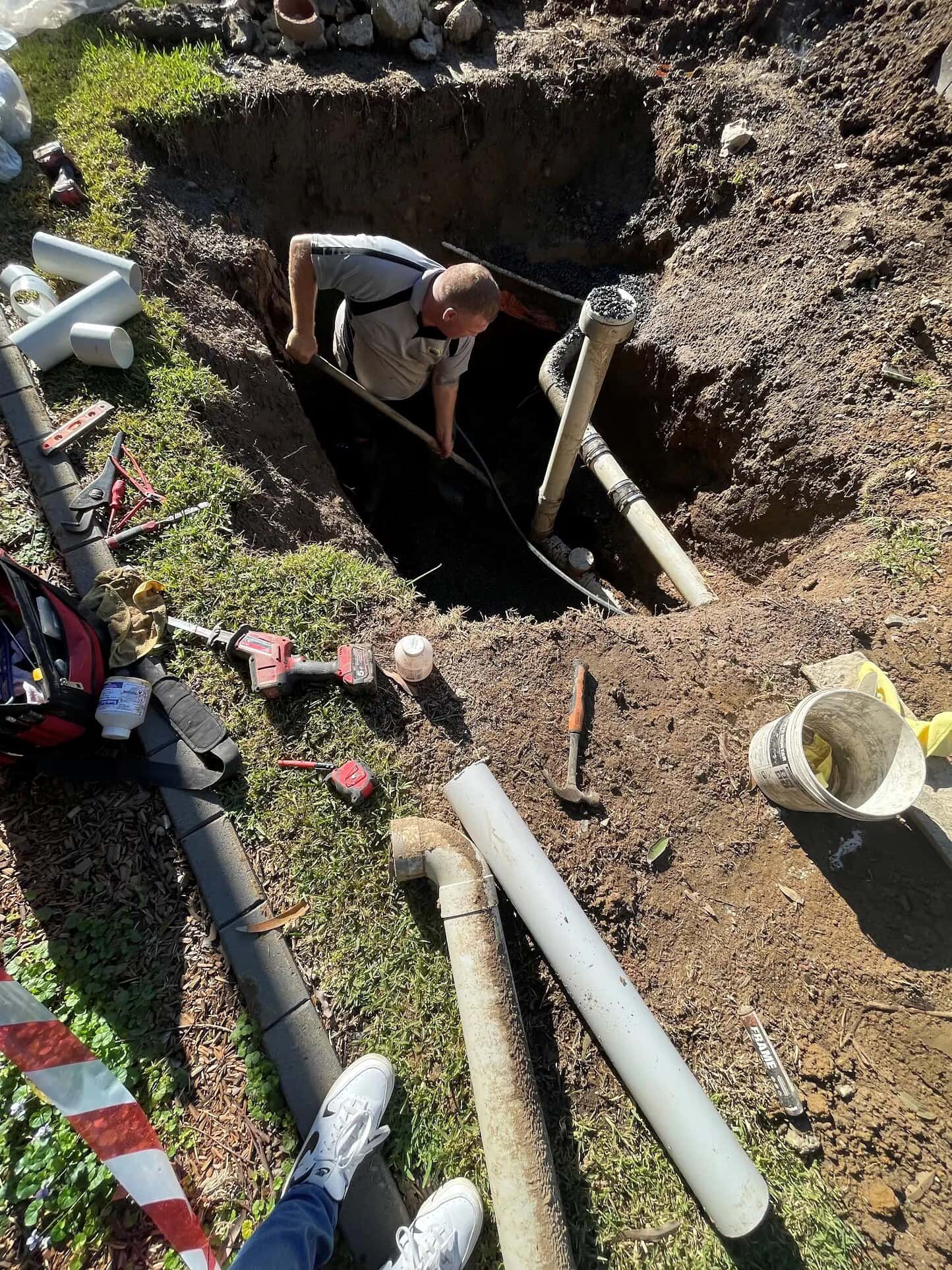 Scott Johnstone working beside replacement sewer pipework in an open trench