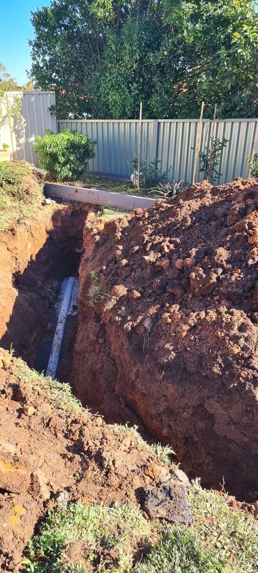 New PVC sewer pipe running through an excavated yard trench
