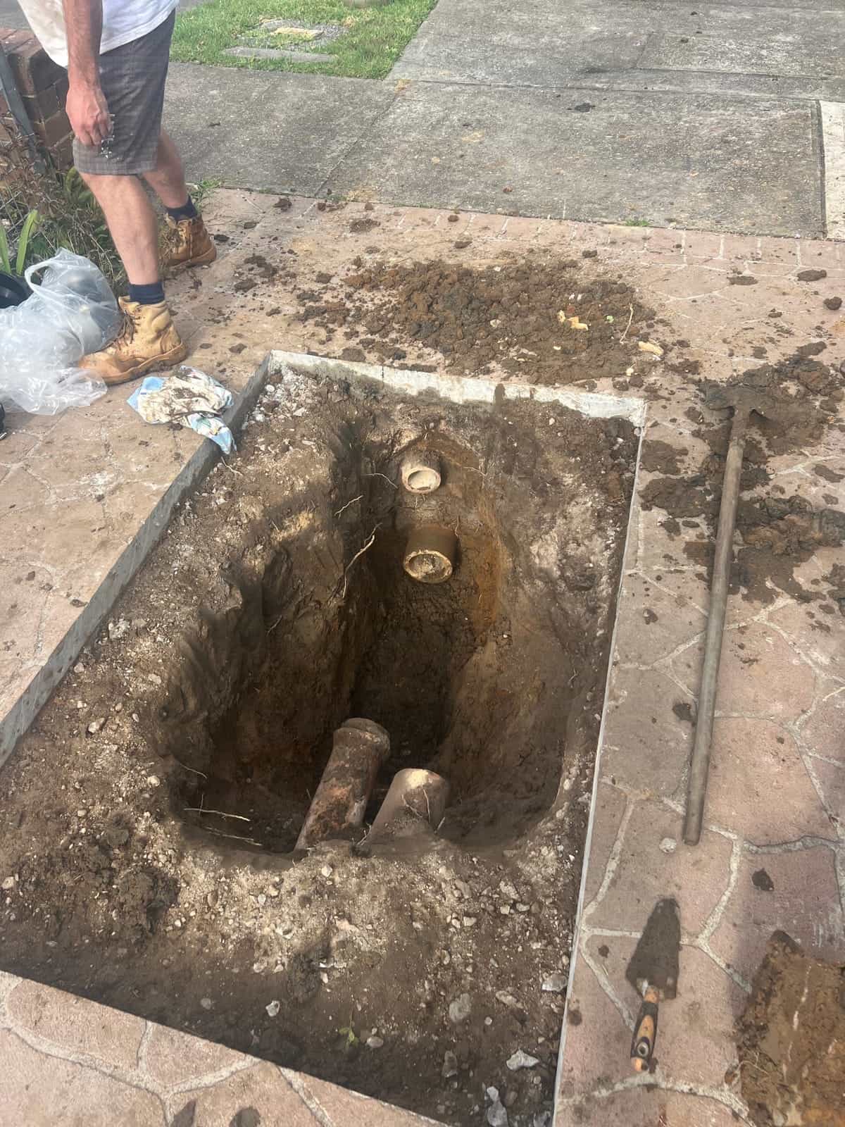 Excavated stormwater drainage trench beside paving