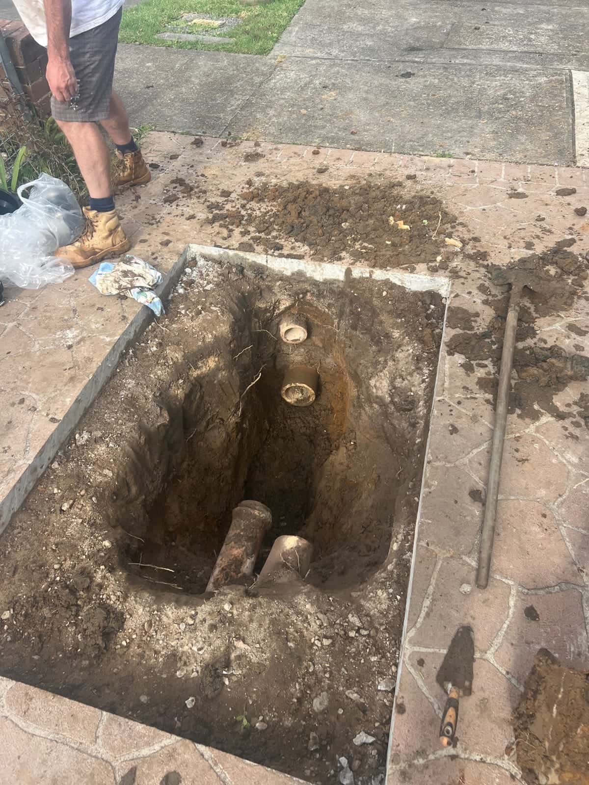 Excavated stormwater drainage trench beside paving