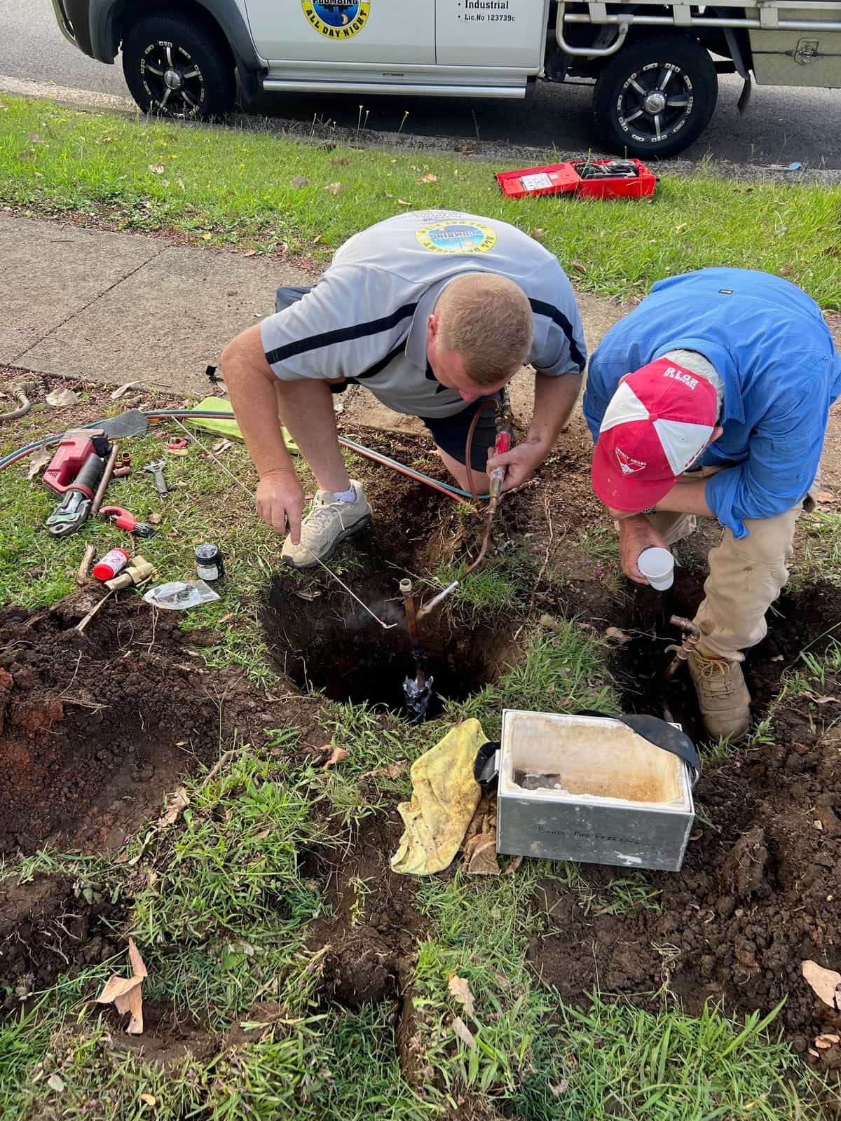 Two plumbers reconnecting a water meter after sewer replacement work