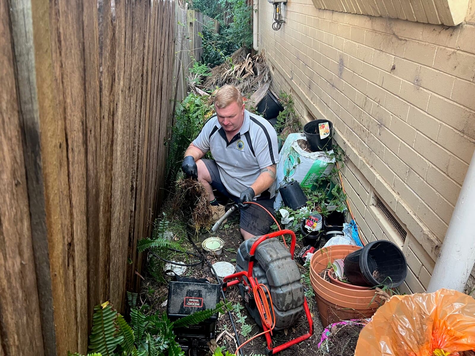 Scott Johnstone clearing roots from an outdoor drain access