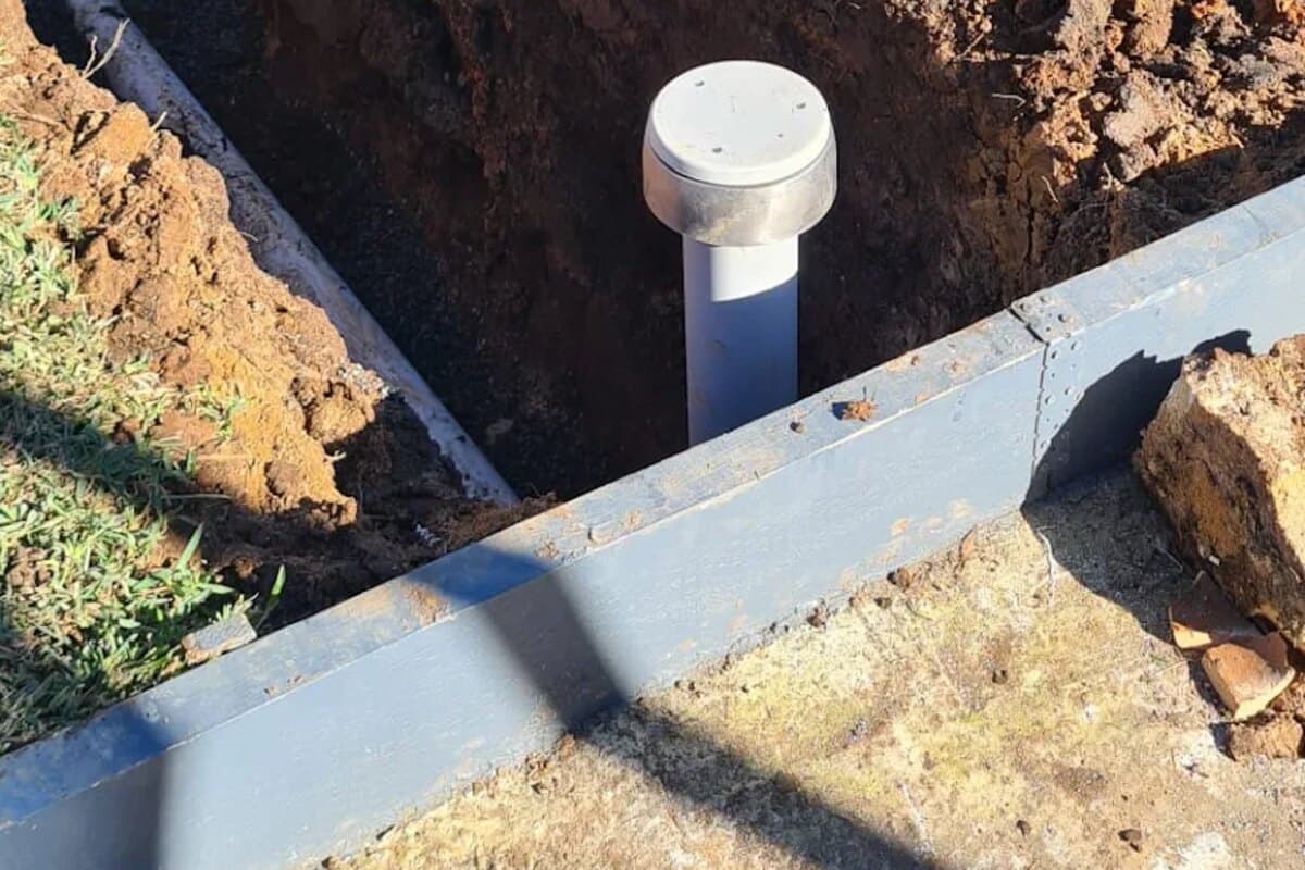 New PVC sewer pipe and capped inspection riser in a deep yard trench