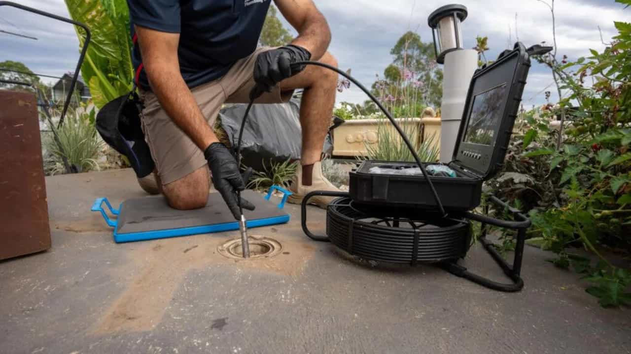 CCTV drain camera cable feeding into an outdoor inspection opening