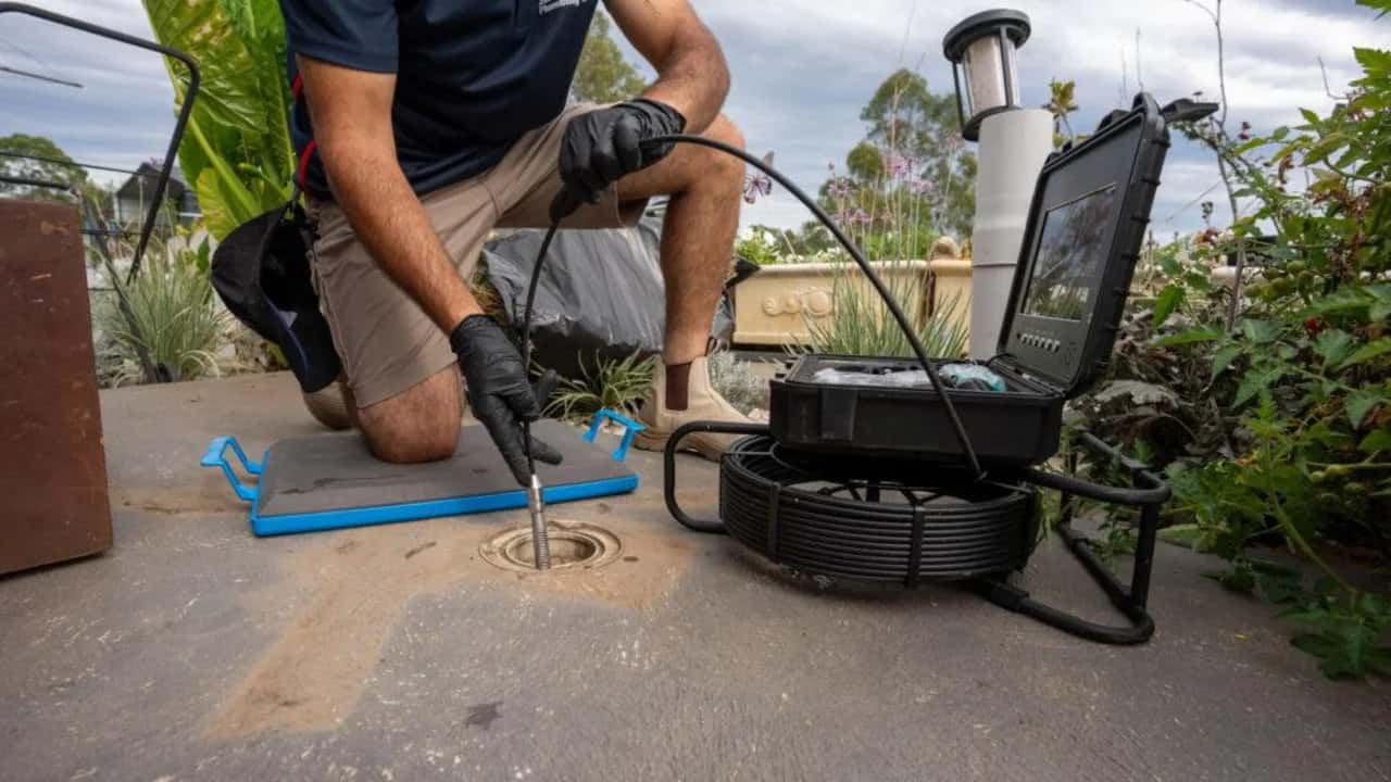 CCTV drain camera cable feeding into an outdoor inspection opening
